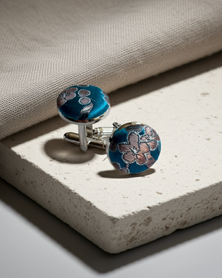 Blue floral patterned cufflinks on a textured surface