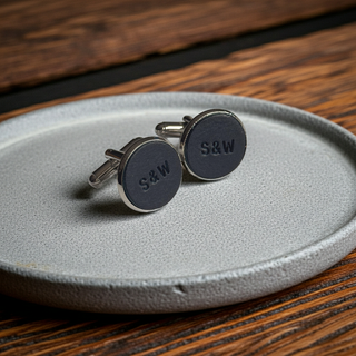 Navy Cufflinks with 'S&W' engraving on a gray plate, wooden background