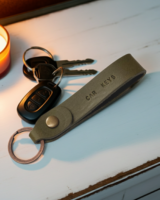 Leather Keychain with keys on a wooden surface next to a lit candle