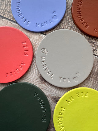 putty coloured leather coaster stamped with 'herbal tea' around the edge of the coaster.