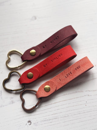 Red leather keychains with heart-shaped keyrings on a white background