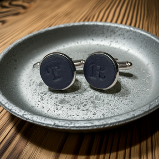 Pair of Navy cufflinks with initials on a textured gray plate