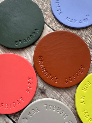 Tan painted leather coasters stamped with 'Grandpa's Coffee' around the edge.