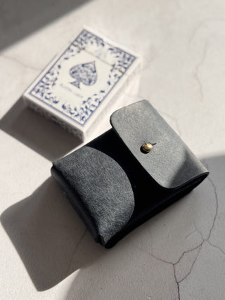 Dark navy leather pouch with a gold button on a light grey surface