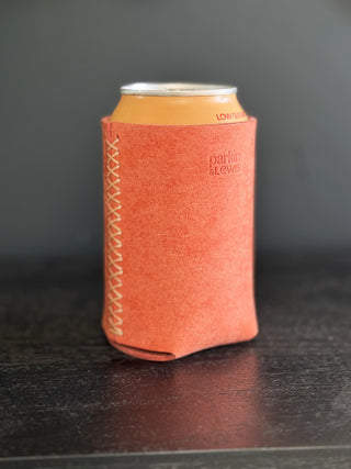 Pink can cooler with white stitching on a dark surface and gray background