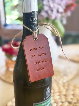 Wine bottle with a personalized leather tag on a blurred background